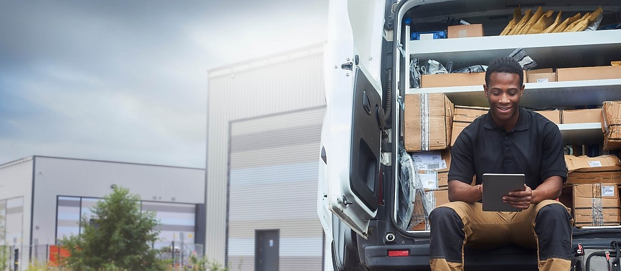 Delivery driver on tablet sat in van