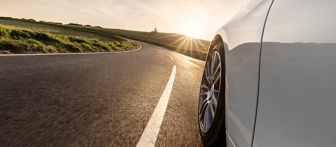 White car driving into sunset