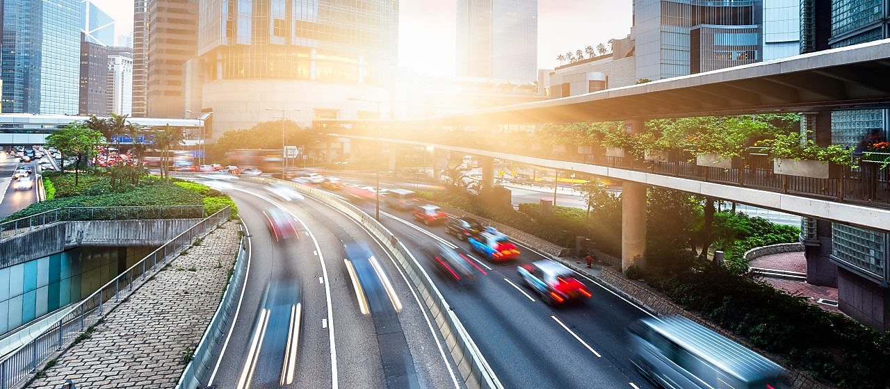 Busy city road with sunlight shining through buildings