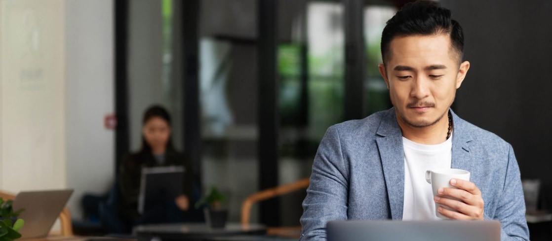 Man drinking coffee while on laptop