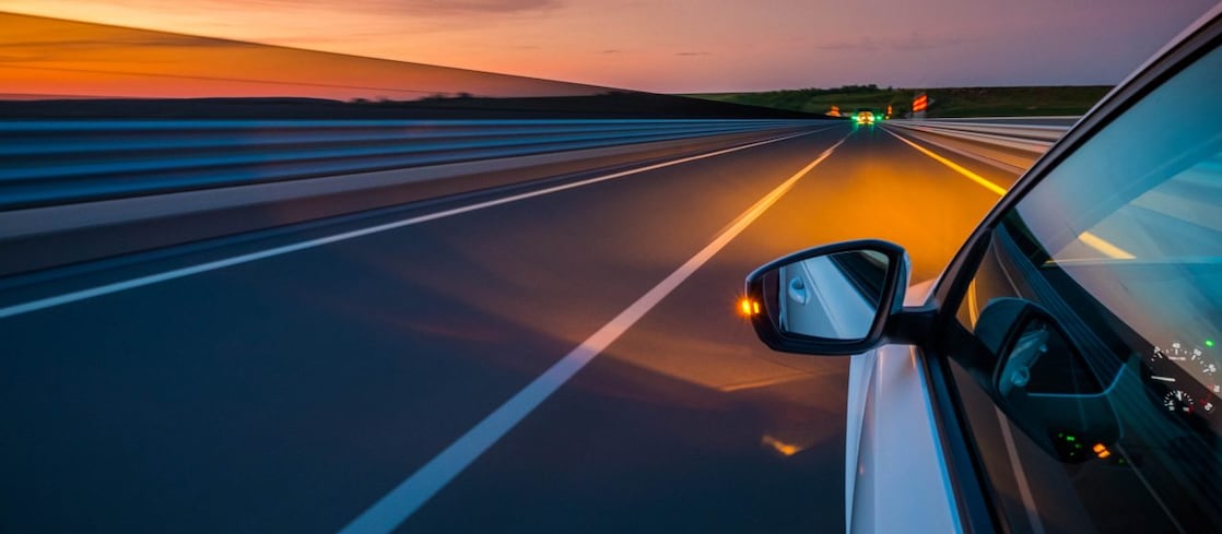 White car driving into sunset