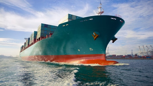 Large container ship siling next to a port
