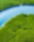 Aerial view of a coastal wetland with winding waterways, patches of green marsh grasses, and open water reflecting sunlight.