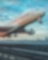 A large commercial airplane taking off from a runway at sunset, with landing gear still extended and the sky filled with colorful clouds.