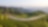 Green terraced tea plantations covering rolling hills with a winding road running through, set against a backdrop of distant mountains.