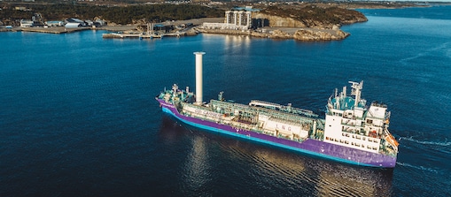 Aerial view of a large Shell vessel on blue water near a coastal industrial site.