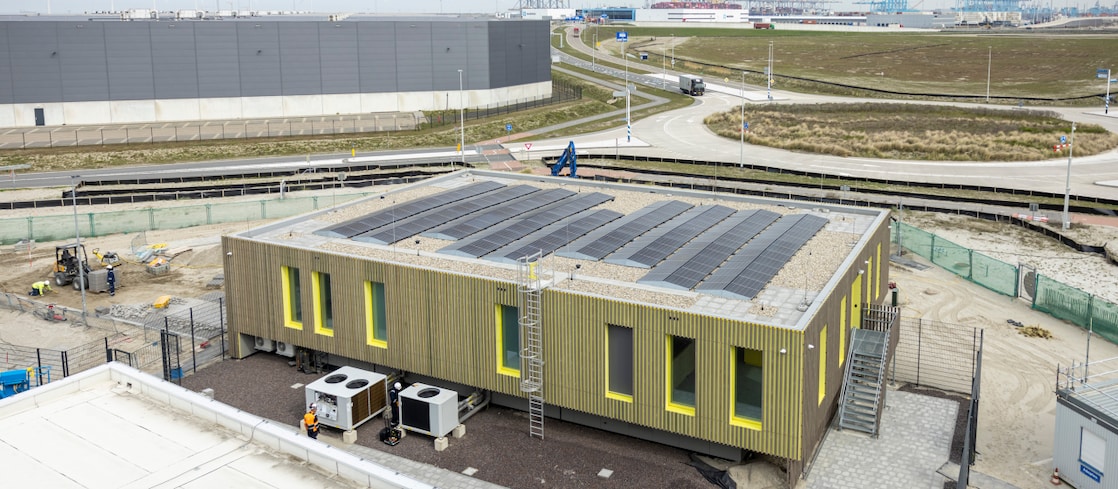 Aerial view of an industrial site featuring storage tanks, pipelines and a building with rooftop solar panels.