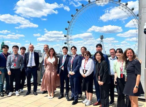 Ross Brown and a group of delegates standing outdoors in London with the London Eye in the background.