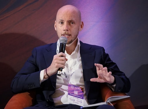 Ross Brown speaking into a handheld microphone during a panel discussion.