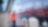 Worker in a high-visibility jacket standing on a tugboat, guiding a large red cargo ship in a busy industrial port.