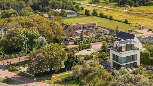 Aerial view of a residential neighbourhood featuring modern homes, trees, gardens, and surrounding green spaces.