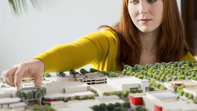 Caucasian businesswoman examining scale model