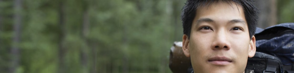 Portrait of Asian male backpacker in the woods