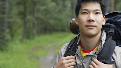 Portrait of Asian male backpacker in the woods
