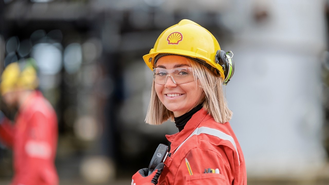 smiling woman posing in yellow hard hat with Shell logo