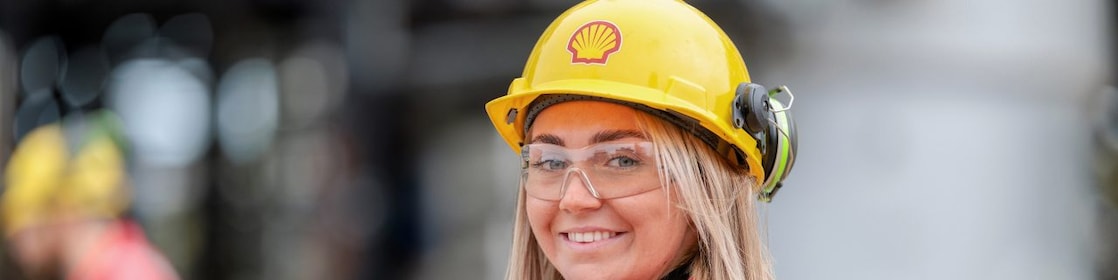 Smiling woman posing in yellow hard hat with Shell logo