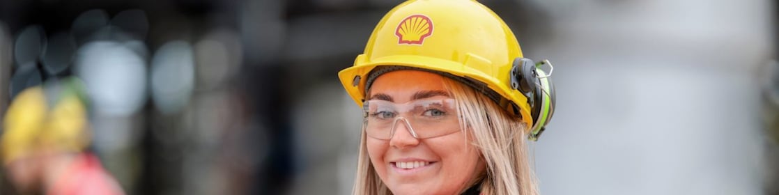 Smiling woman posing in yellow hard hat with Shell logo
