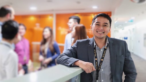 Jason leaning on a cabinet with team members out of focus behind him