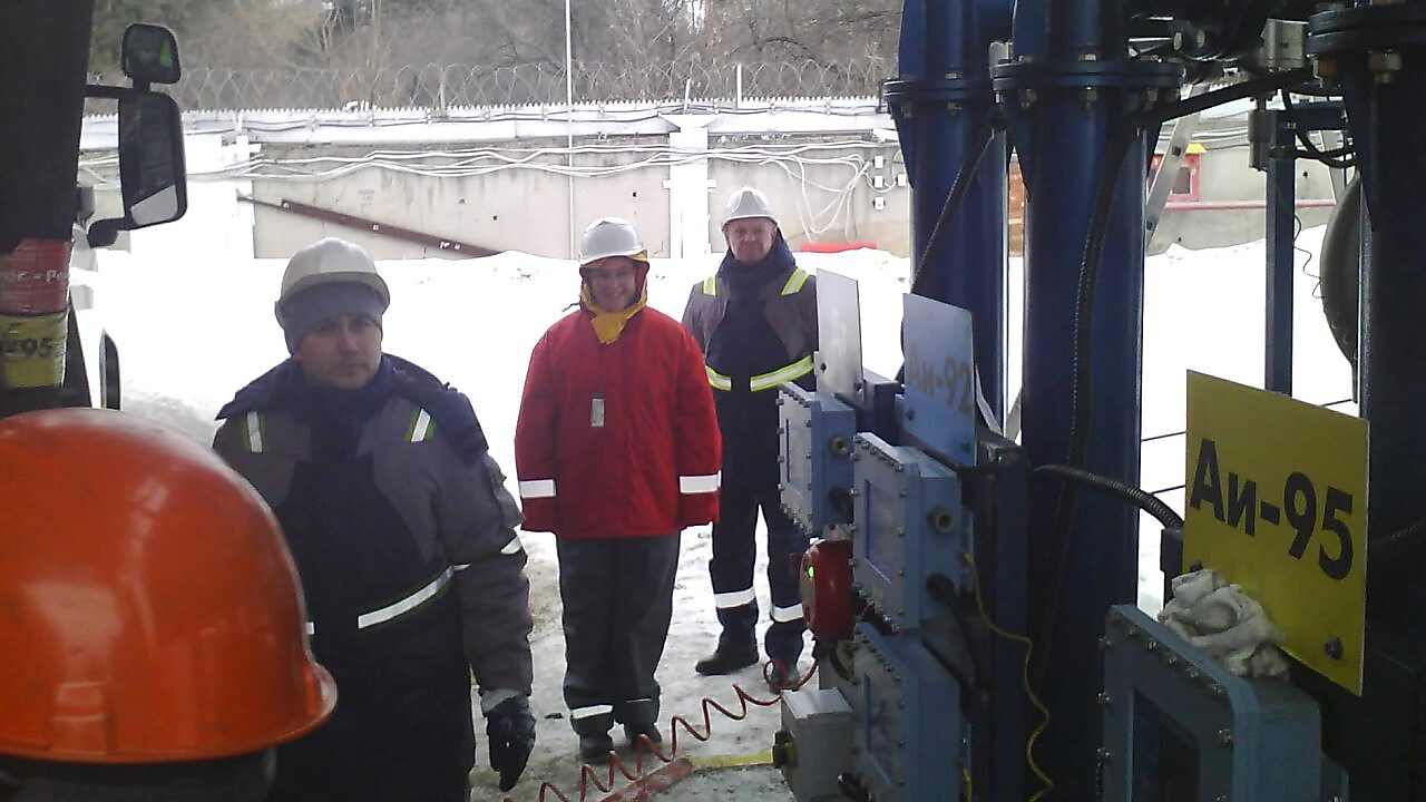 Krisztina dressed in safety gear at a 3rd party terminal with a local manager and driver