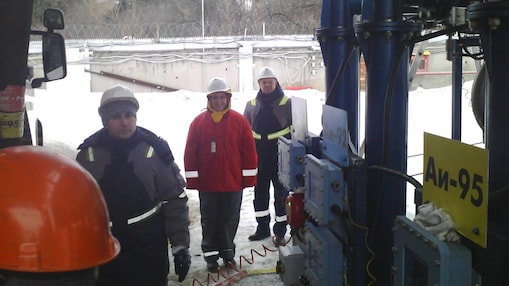 Krisztina dressed in safety gear at a 3rd party terminal with a local manager and driver