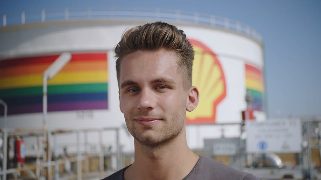 A male Shell employee standing in front of a refinery with rainbow colors