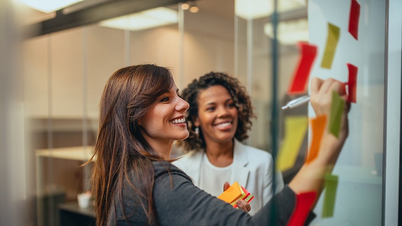 Woman writing on board and smiling