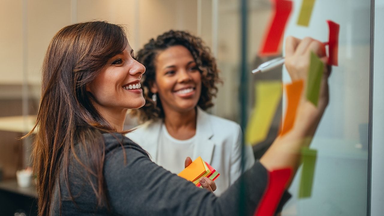 Woman writing on board and smiling
