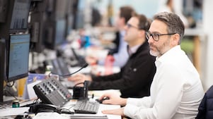 man in a white shirt and glasses focused at his desk