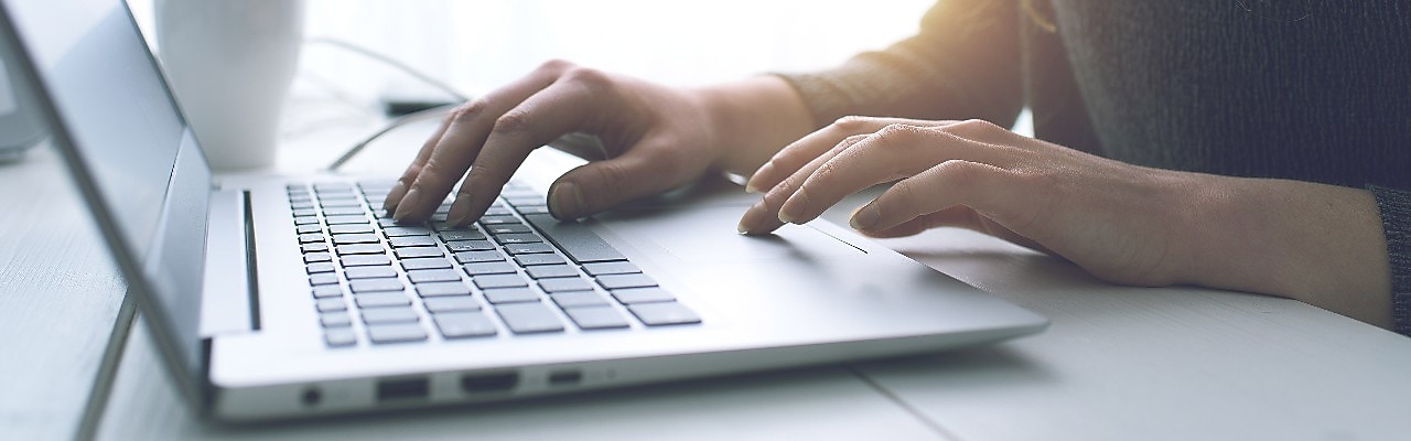 silver laptop with hands typing on it