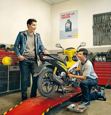 two motorcyclists changing the oil on a motorbike