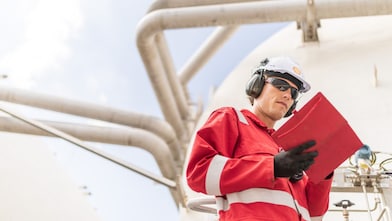 Engineer in a red suite reading  documents on site