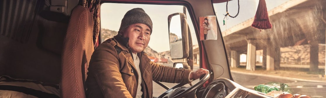 Chinese truck driver smiling in the cab of his truck in Shanghai