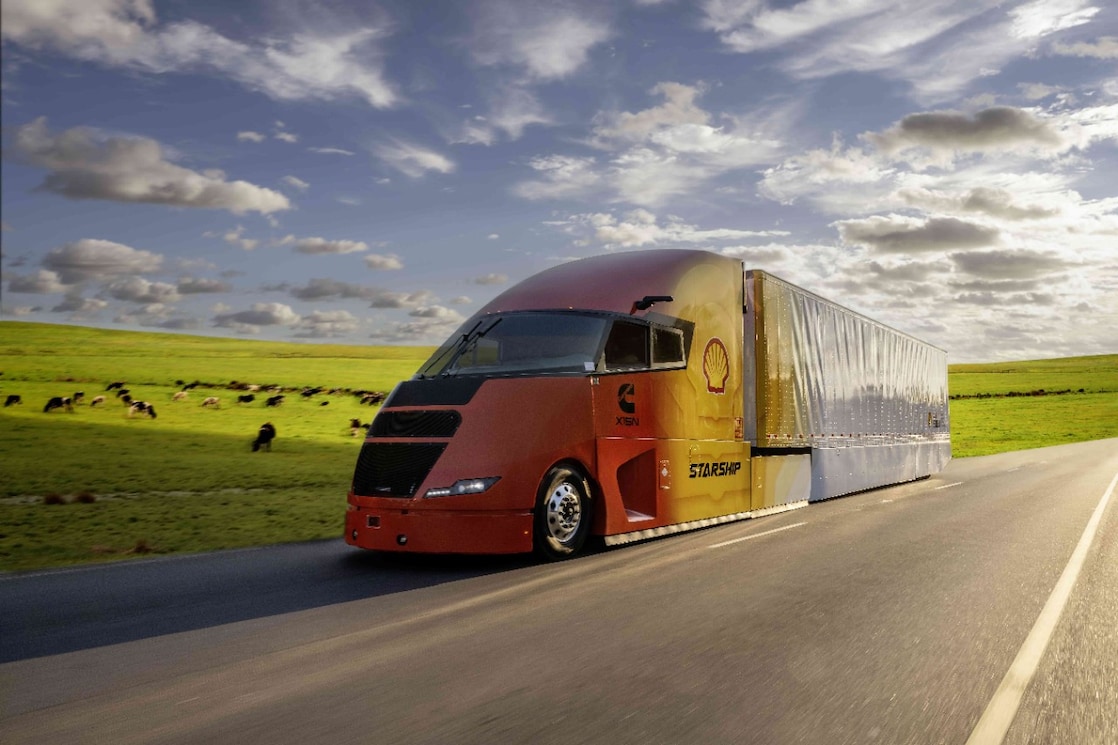 side view of the Starship 3.0 truck driving by a field of cows.