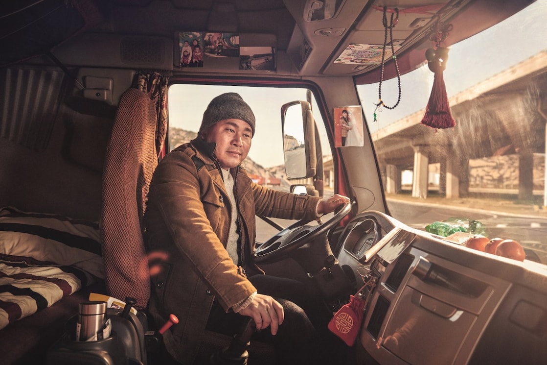 Chinese truck driver smiling in the cab of his truck in Shanghai