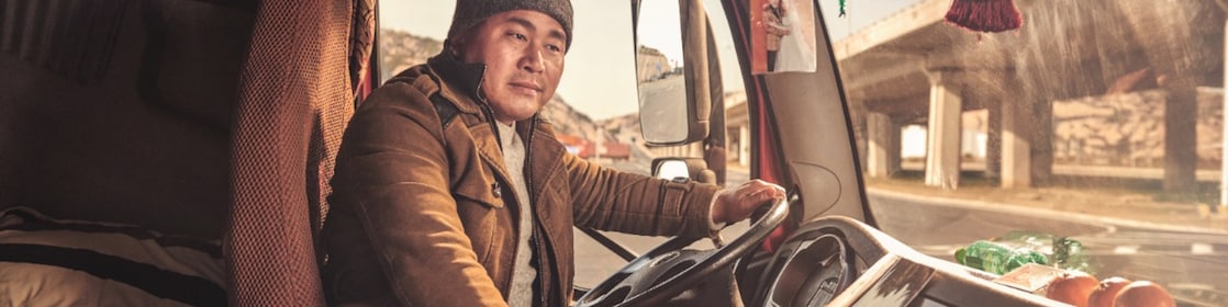 Chinese truck driver smiling in the cab of his truck in Shanghai