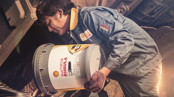 Truck driver pouring Rimula lubricant into his truck engine