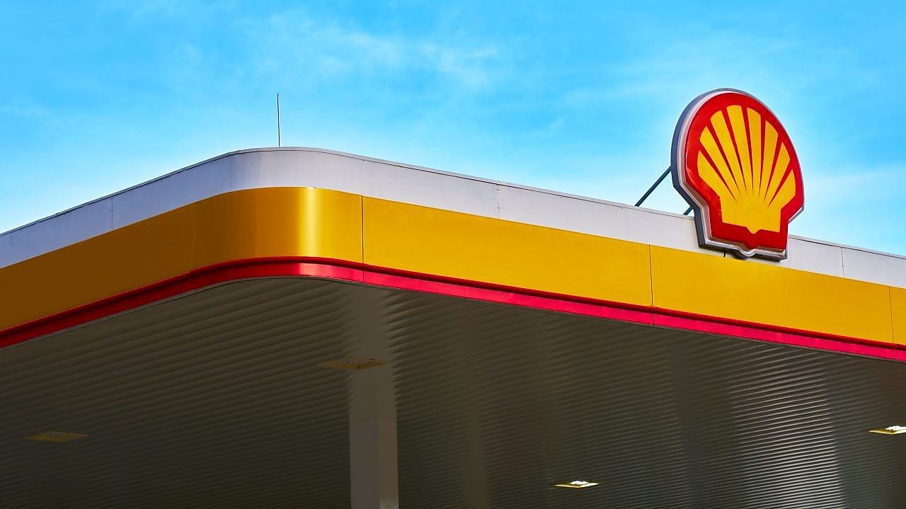 Shell service station canopy with the Shell logo against a blue sky.