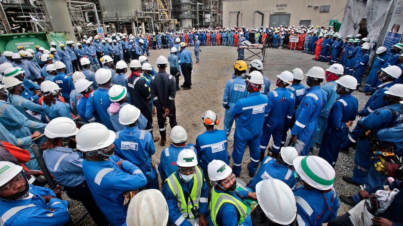 Dozens of workers wearing hard hats and blue coveralls gather at the Nigeria LNG site.​