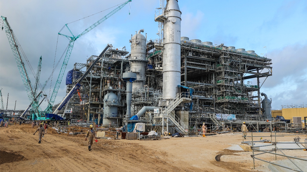 Industrial structures, cranes and scaffolding stand at the Nigeria LNG Train 7 construction site, with workers moving around the facility.​