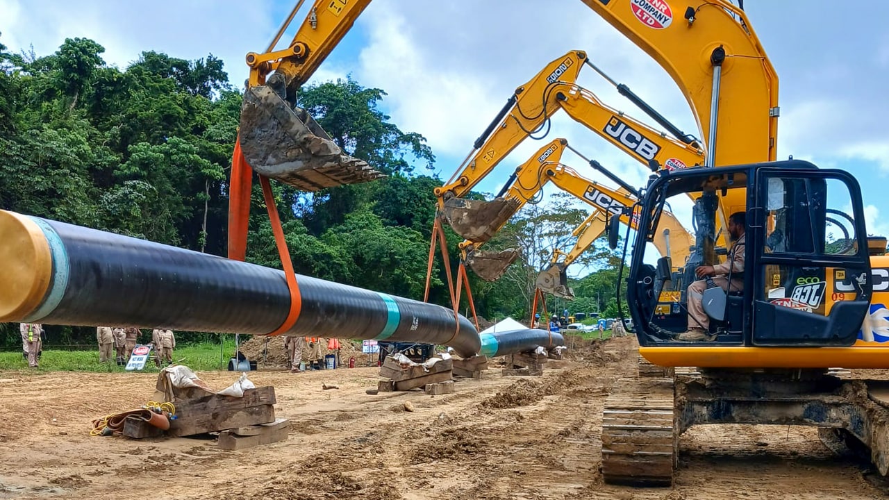 Yellow excavators position a section of pipeline during construction of the onshore pipeline that will connect the Manatee platform to the Beachfield facility.​