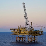 The Crux offshore platform stands in open water, with a tall central tower rising above the facility.