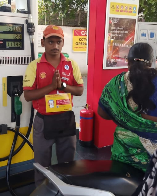 Vijay Algade, a hearing disabled pump attendant at the Shell service station on Senapati Bapat Road in Pune, India, greets a customer