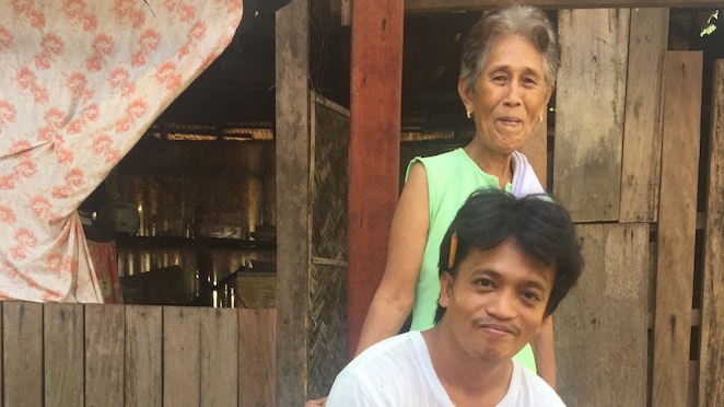 Gerald Tria takes a break with his grandmother, Lilia Molato, in front of her home. Image: Lech Mintowt-Czyz