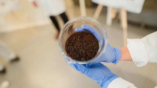 A Nature Energy laboratory worker holds a beaker of the leftover residue from biomethane production, which is given back to farmers as fertiliser