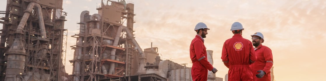 Three Shell workers talking in from of a cement plant