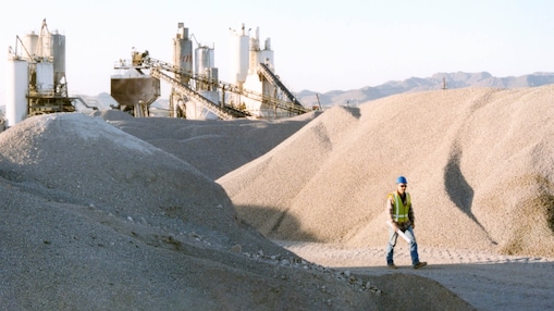 Man walking outside cement plant in high vis