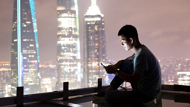 Man sitting on rooftop with mobile in hand