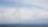 A row of white offshore wind turbines stretching into the distance, installed in the ocean under a partly cloudy sky.