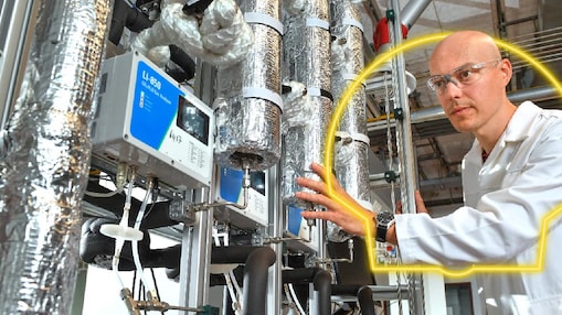 Technician adjusting instruments on insulated pipes used for CO₂ capture.