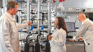 Engineers in lab coats inspecting carbon capture research equipment